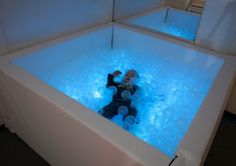 a person in a bathtub with blue lights on the sides and water around it