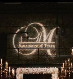 the wedding arch is decorated with flowers and lit candles in front of a brick wall