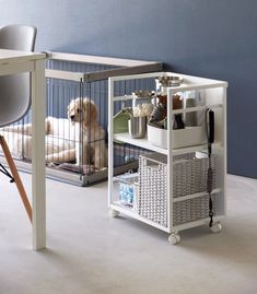 a dog sitting in a cage next to a table