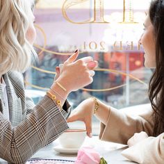 two women sitting at a table talking to each other