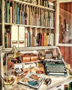 an old typewriter sitting on top of a desk next to a book shelf filled with books