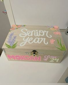 a small wooden box with flowers painted on it's sides and the words senior year written in white