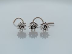 two small silver earrings with spiral designs on the end, sitting on a white surface