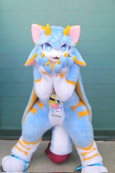 a blue and orange stuffed animal standing on its hind legs in front of a garage door