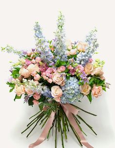 a bouquet of pink and blue flowers on a white background with a ribbon tied around it