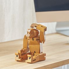 a wooden toy sitting on top of a desk next to a computer monitor and keyboard