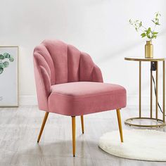 a pink chair sitting on top of a hard wood floor next to a white rug