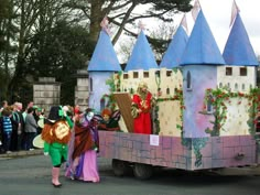 people in costumes are riding on the back of a truck with an elaborate castle design