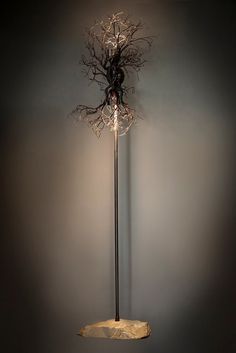 a tall metal pole with a light on it's head and branches hanging from the side