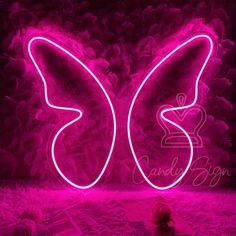 a pink neon butterfly sitting on top of a bed