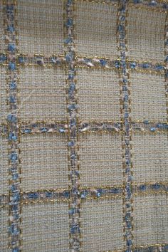 closeup of the fabric with blue and beige squares on it, as well as some gold thread