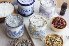 several jars filled with different types of food on top of a wooden table next to bowls and spoons