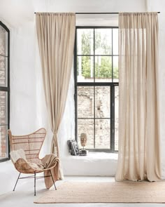 an open window with curtains and a chair in front of it, next to a brick wall