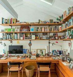 a home office with bookshelves full of books and pictures on the wall above it