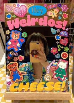 a woman taking a selfie in front of a sign with stickers on it