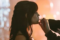 a woman is getting her make up done in front of a mirror with lights behind her