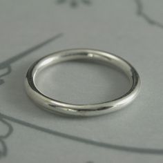 a close up of a wedding ring on a sheet of paper with flowers in the background