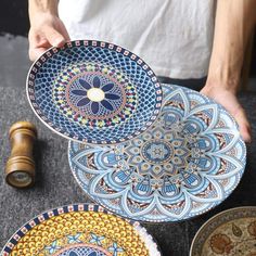 a person holding three plates with designs on them