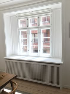 an empty room with a table, chair and radiator in front of the window