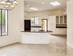 an empty kitchen with white cabinets and marble counter tops, is pictured in this image