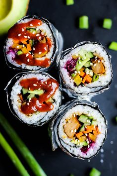 four sushi rolls with vegetables and sauce on them