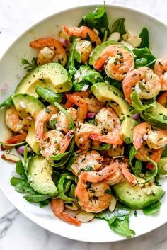 shrimp and avocado salad in a white bowl on a marble countertop with dressing