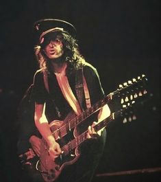 a man with long hair playing an electric guitar