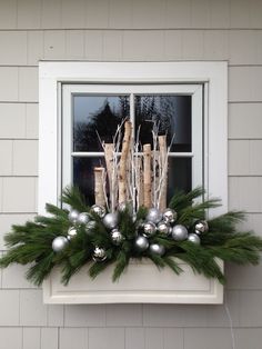 a window sill decorated with silver ornaments and greenery in front of a house