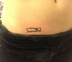 a woman's stomach with a small boat tattoo on her lower side ribcage