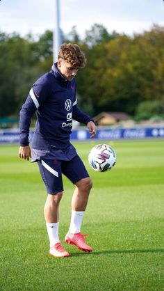 a young man kicking a soccer ball on top of a field