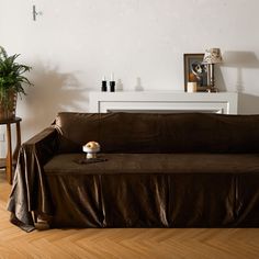 a brown couch sitting on top of a hard wood floor next to a white table