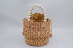 a woven bag with white beads on the handles and handle is sitting in front of a white background