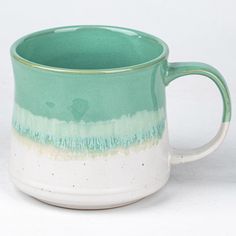 a green and white coffee mug sitting on top of a table