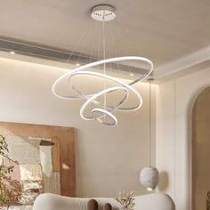 a modern chandelier hanging from the ceiling in a living room with white furniture