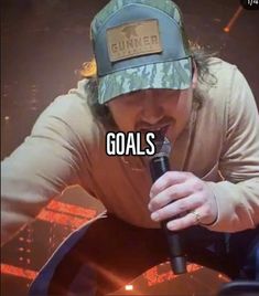 a man holding a microphone with the words goals on it