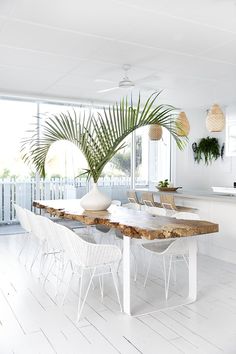 a dining room table with white chairs and a potted plant on the top of it