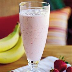 there is a strawberry milkshake on the table next to bananas and strawberries