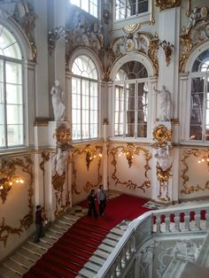 two people are walking down the red carpeted stairs in an ornately decorated building