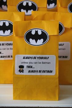 some yellow bags with batman stickers on them are lined up in a row to be used as favors