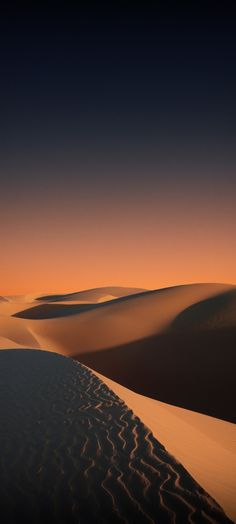 the sun is setting over an expanse of sand dunes