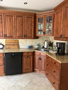 a kitchen with wooden cabinets and tile flooring, black dishwasher on the counter