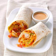 a white plate topped with a burrito and dipping sauce