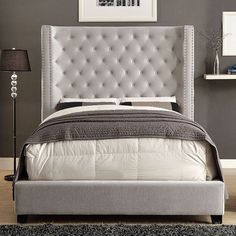 a bed with a white headboard and grey walls