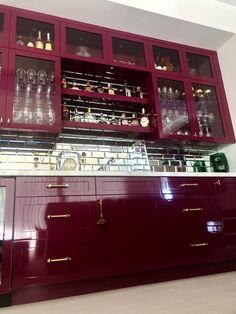 the cabinets in this kitchen are painted red and have glass doors that open to reveal wine glasses