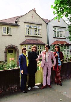 four people standing in front of a house