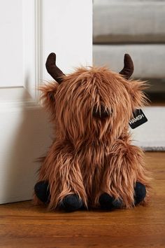 a brown stuffed animal sitting on top of a wooden floor next to a white door