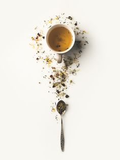 a cup of tea and spoon on a white surface