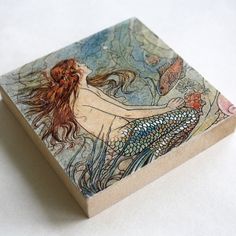 a tile with a mermaid sitting on top of it