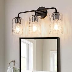 a bathroom vanity light with three jars on it