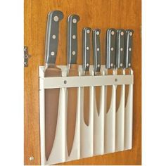 there are many knives hanging on the wall in this kitchen rack that is made out of white plastic